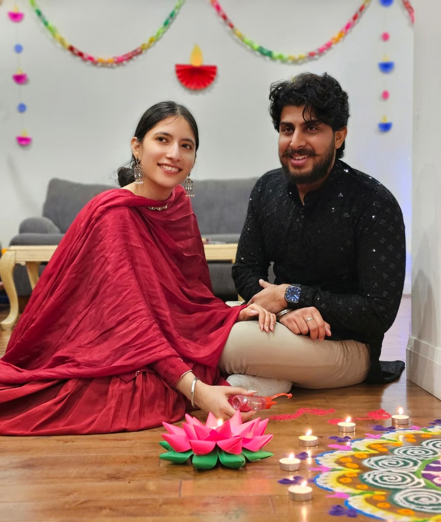 Kamal and Ishmeet sitting with diyas and a rangoli