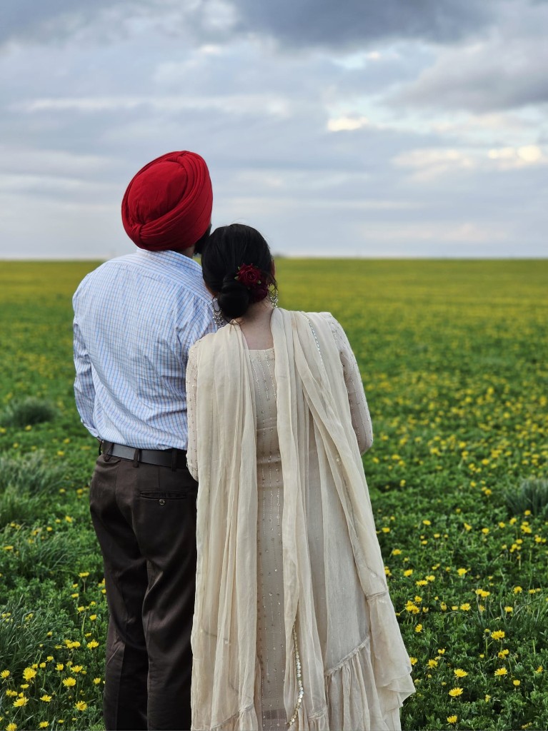 Kamal and Ishmeet standing together in a field of yellow flowers